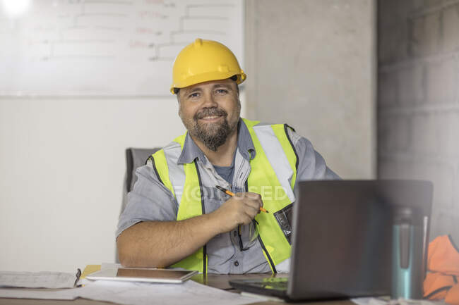 Construction worker using laptop at desk — Stock Photo