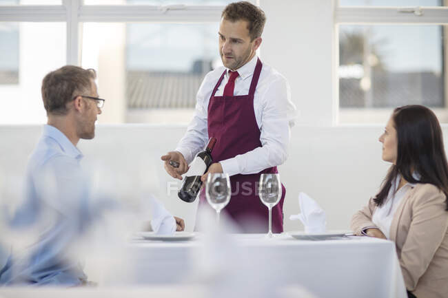 Camarero mostrando botella de vino para cenar en restaurante - foto de stock