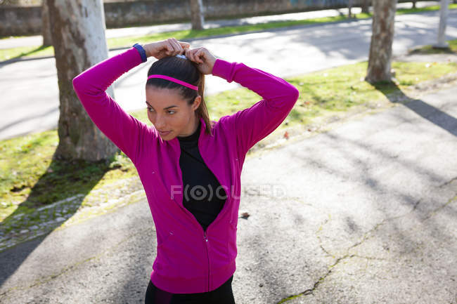 Молодая женщина на улице завязывает волосы в хвостик — стоковое фото