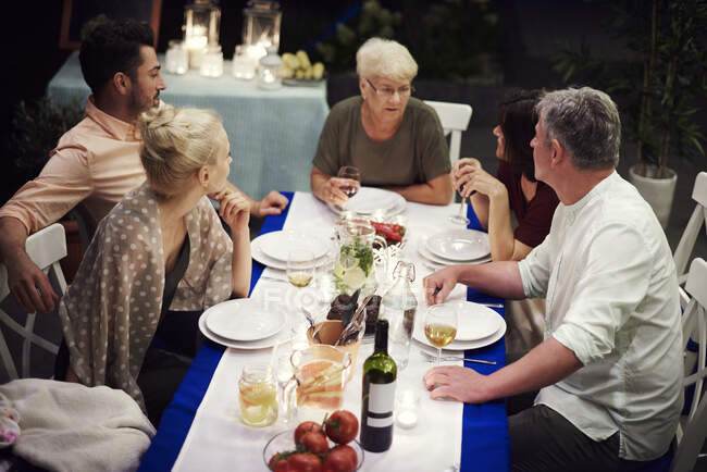 Grupo de personas sentadas a la mesa, disfrutando de la comida - foto de stock
