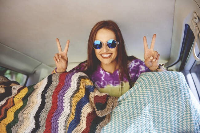 Portrait of young boho woman making peace sign in recreational van — Stock Photo