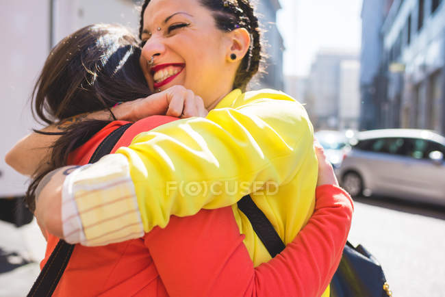 Giovani donne che si abbracciano in strada, Milano, Italia — Foto stock