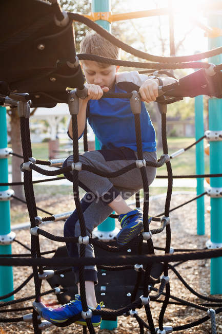 Menino brincando no quadro de escalada no playground — Fotografia de Stock