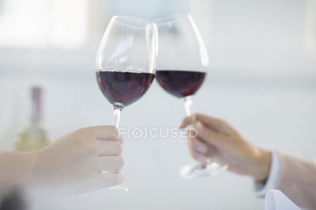 Comedores en restaurante sosteniendo copas de vino, haciendo un brindis, primer plano - foto de stock