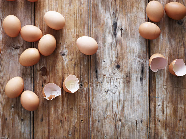 Eggs and egg shells on wooden surface, overhead view — Stock Photo