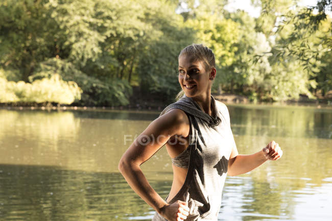 Happy young female running by lake in park — Stock Photo