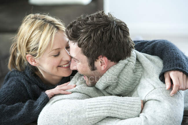 Happy couple in polo neck sweaters gazing at each other — Stock Photo