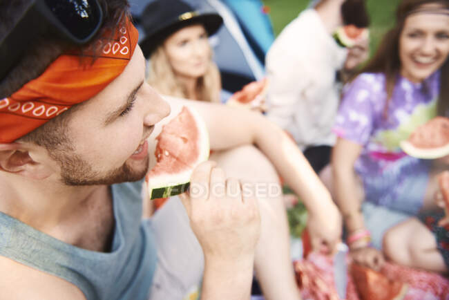 Jeunes amis adultes boho manger des tranches de melon au festival — Photo de stock