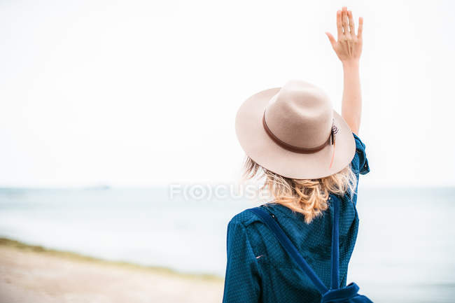 Женщина, стоящая на пляже с рукой в воздухе — стоковое фото
