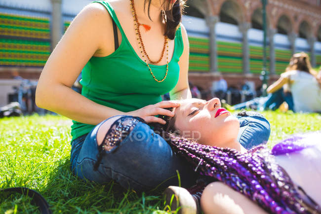 Donna che fa un massaggio alla testa amico sull'erba, Milano, Italia — Foto stock