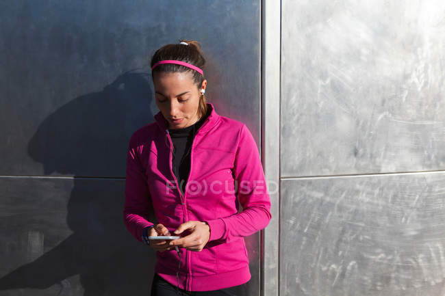 Jovem mulher em roupas esportivas mensagens de texto no smartphone — Fotografia de Stock