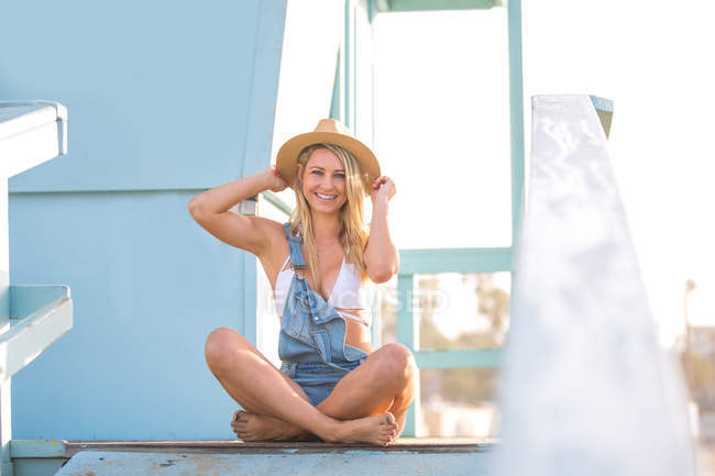 Ritratto di giovane donna a gambe incrociate su capanna da spiaggia, Santa Monica, California, USA — Foto stock