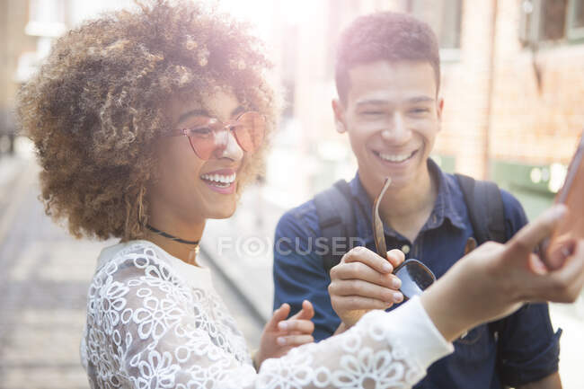 Young man and woman outdoors, taking selfie, using smartphone — Stock Photo
