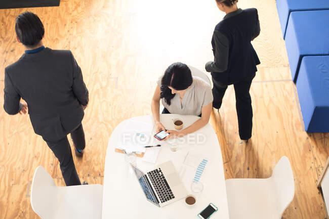 Vista ambientale di tre donne di affari e gli uomini riuniti a tavolo ufficio — Foto stock
