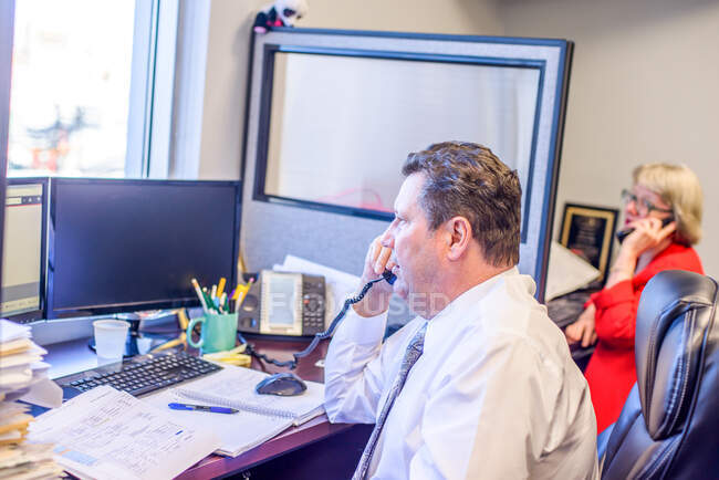 Männliche und weibliche Büroangestellte telefonieren am Schreibtisch — Stockfoto