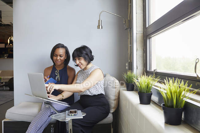 Две деловые женщины, работающие с ноутбуками в современном офисе — стоковое фото