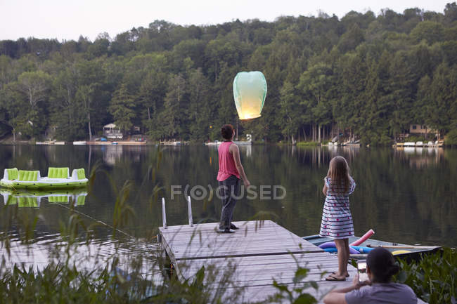 Girls releasing sky lantern and woman photographing event — Stock Photo