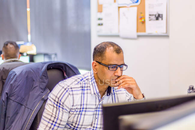 Чоловік офісний працівник дивиться на настільний комп'ютер за офісним столом — стокове фото