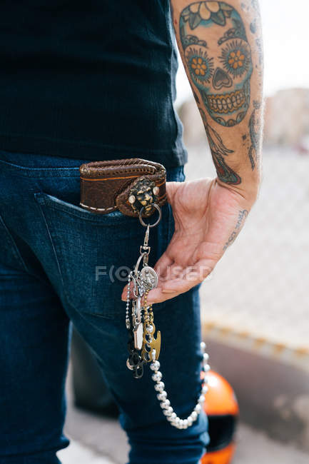 Visão traseira do homem com chaves no bolso traseiro e tatuagem de crânio, cortado — Fotografia de Stock