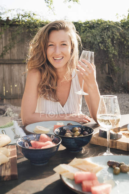 Retrato de una joven sosteniendo una copa de vino en la mesa - foto de stock
