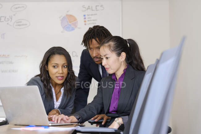 Empresarios y mujeres de negocios, en la oficina, lluvia de ideas, utilizando el ordenador portátil - foto de stock