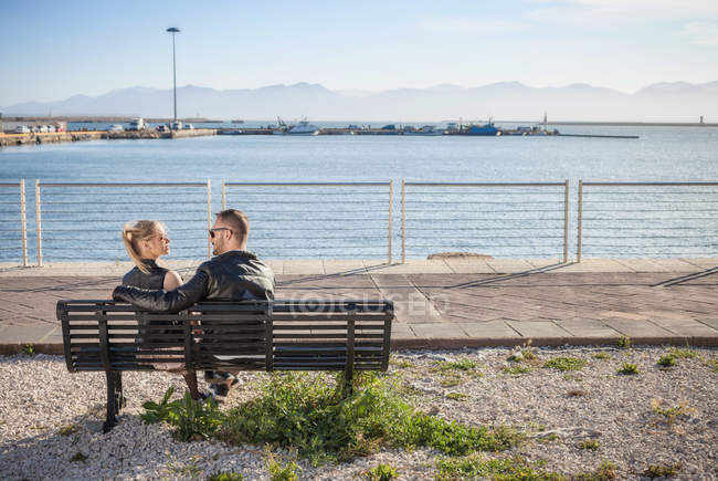 Rear view of couple sitting on bench, Cagliari, Sardinia, Italy, Europe — Stock Photo