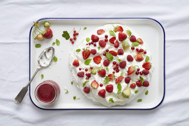 Top view of pavlova dessert with redcurrants, strawberries and fresh mint on serving tray — Stock Photo