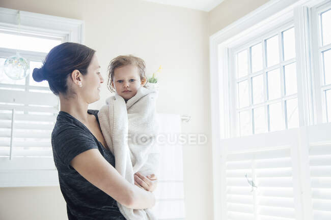 Mother holding daughter wrapped in towel — Stock Photo
