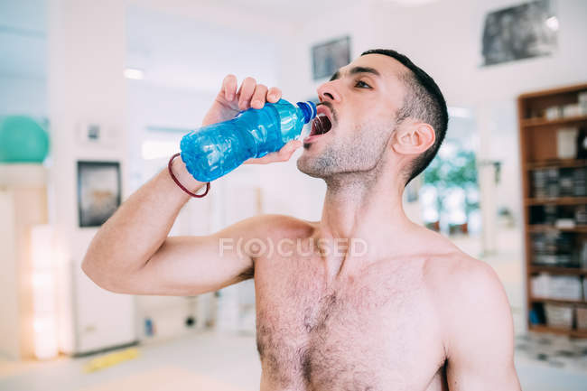 Чоловік п'є з пляшки води в спортзалі — стокове фото