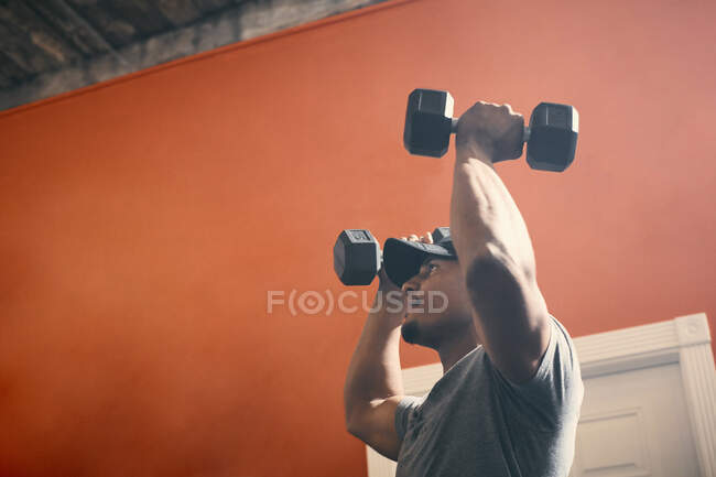 Homme utilisant des haltères dans la salle de gym — Photo de stock