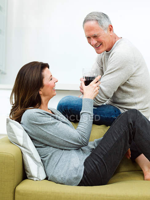 Couple d'âge mûr assis sur un canapé avec du vin — Photo de stock