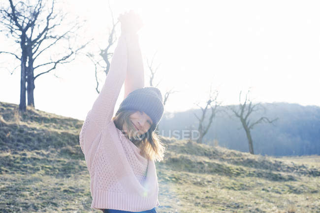 Portrait of woman with arms raised in sunlit field — Stock Photo