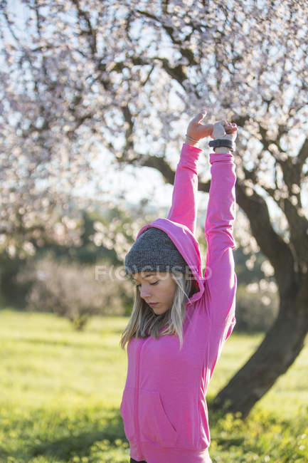 Молода жінка розтягується руками, піднятими на відкритому повітрі — стокове фото
