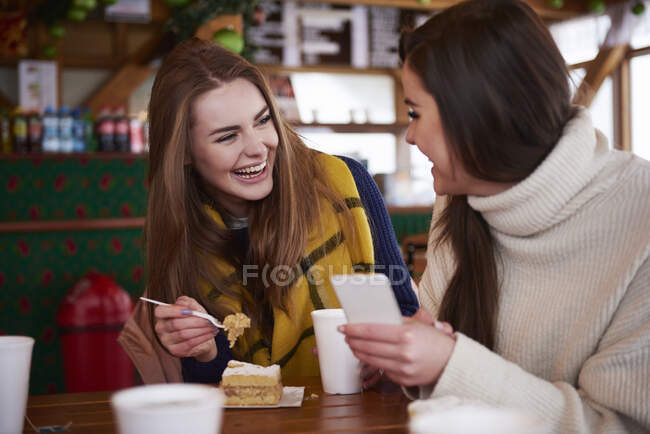 Mujeres jóvenes sonriendo por mensaje de texto en el teléfono móvil - foto de stock
