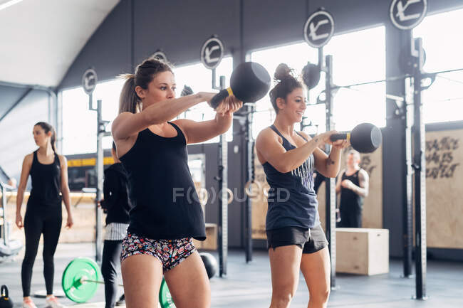 Levantamiento de pesas mujer con campanas de tetera en el gimnasio - foto de stock
