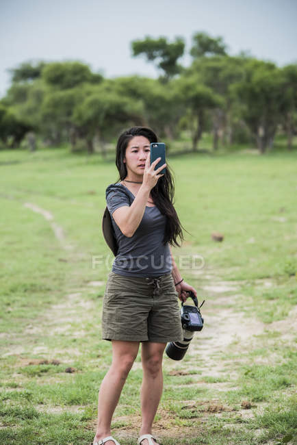 Азиатская молодая туристка фотографирует со смартфоном и камерой, Ботсвана, Африка — стоковое фото