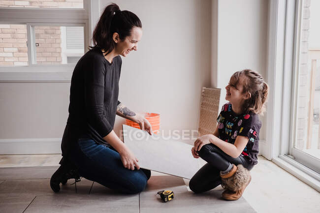 Девушка помогает матери устанавливать плитку для пола — стоковое фото