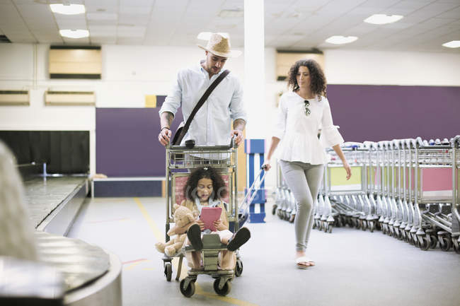 Vater trägt Tochter im Rollkoffer am Flughafen — Stockfoto