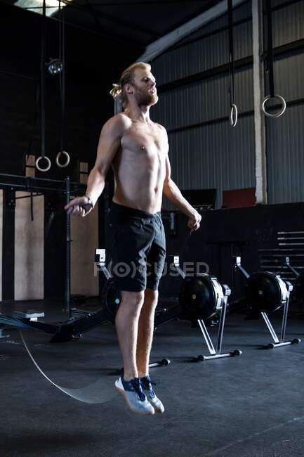 Man exercising in gymnasium, skipping with speed rope — Stock Photo
