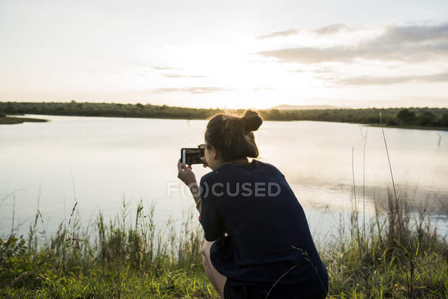 Jeune femme touriste photographiant rivière dans le parc national de Kruger, Afrique du Sud — Photo de stock