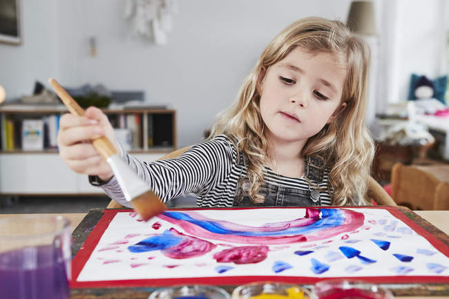 Chica joven pintura cuadro en la mesa - foto de stock