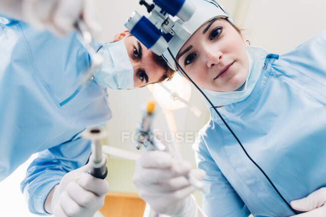 Dentista y enfermera dental tratando al paciente, perspectiva personal - foto de stock