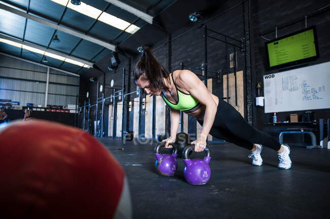 Woman exercising in gymnasium, using kettlebells — Stock Photo