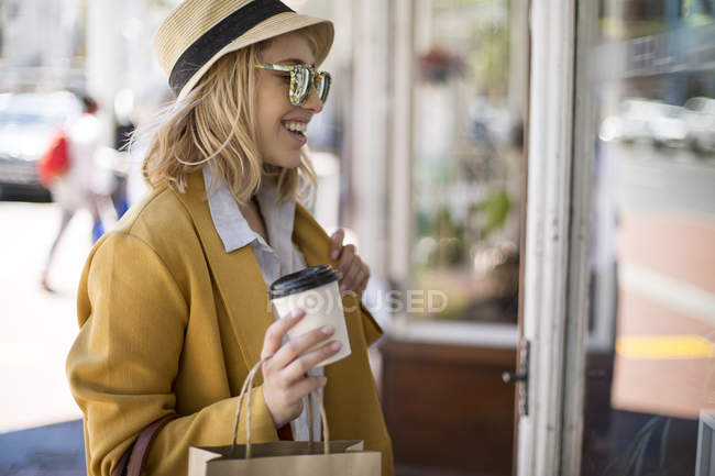 Mujer con café para ir de compras por la ventana, Ciudad del Cabo, Sudáfrica - foto de stock