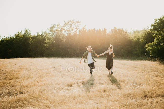 Couple marchant sur le champ d'herbe dorée, Arezzo, Toscane, Italie — Photo de stock