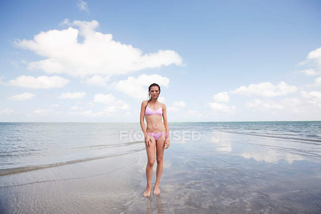 Mujer joven de pie en el mar poco profundo - foto de stock
