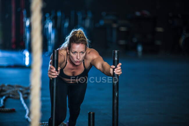 Woman exercising in gymnasium, sled training — Stock Photo