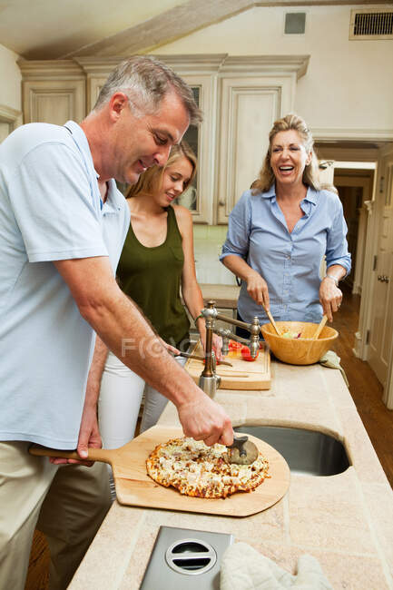 Familie bereitet gemeinsam Pizza in Küche zu — Stockfoto