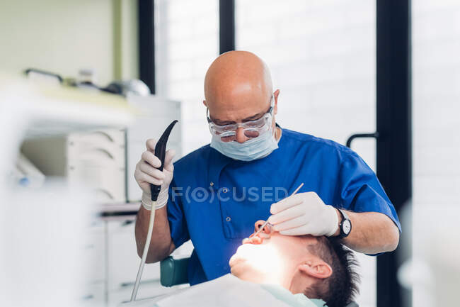 Стоматолог проводит стоматологическую процедуру на пациенте мужского пола — стоковое фото