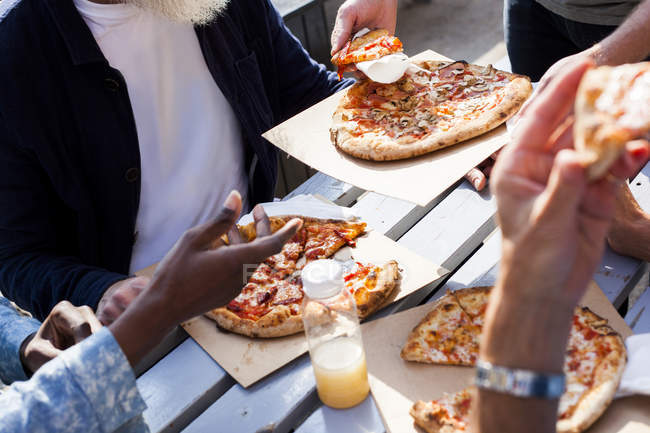 Друзья едят пиццу на открытом воздухе — стоковое фото